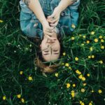 woman lying on grass ground with yellow petaled flowers