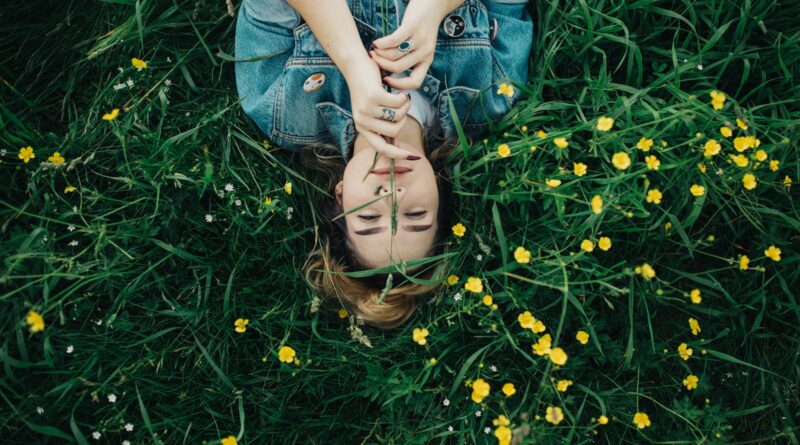 woman lying on grass ground with yellow petaled flowers